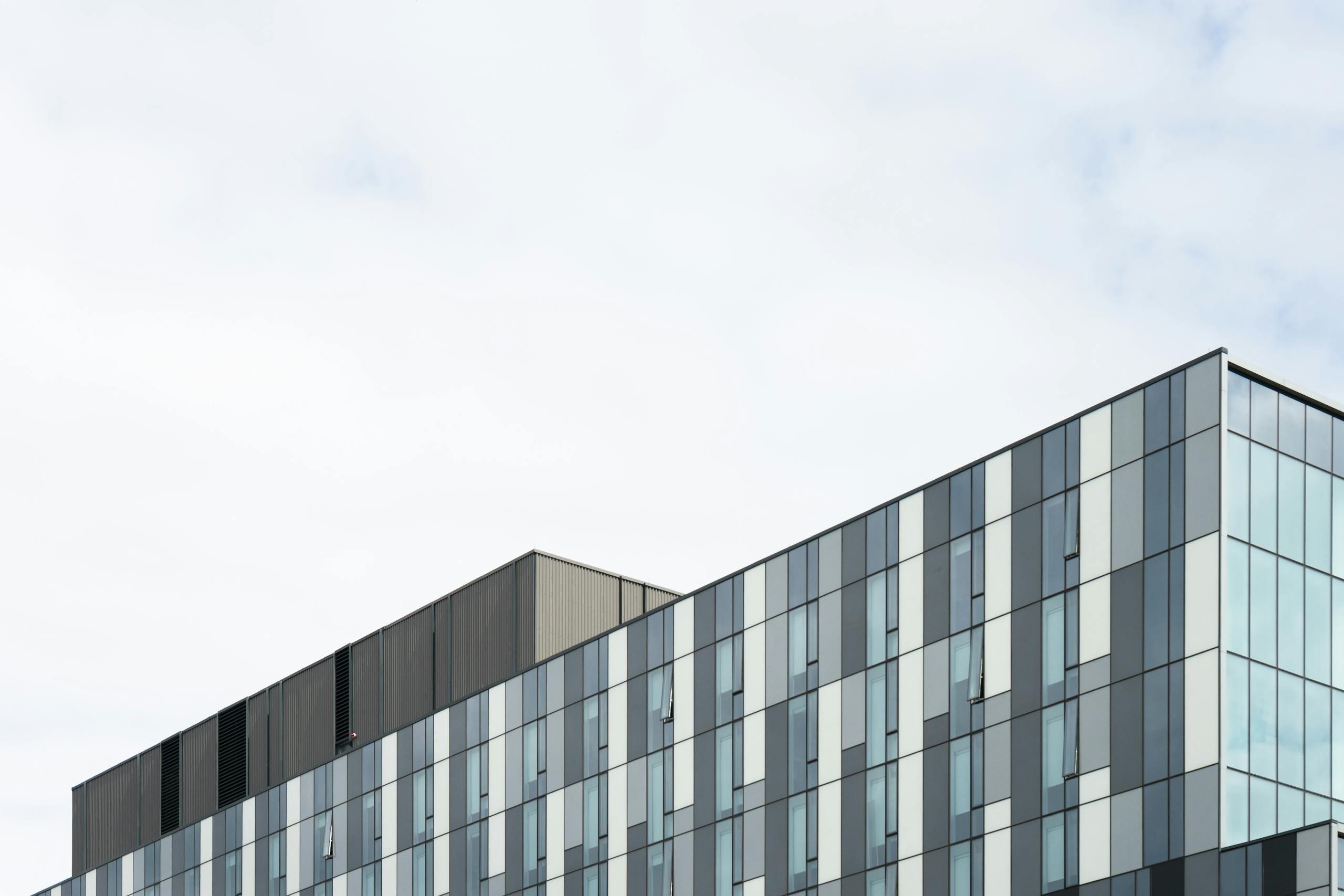 A striking image of modern architecture with geometric glass panels reflecting a clear blue sky.